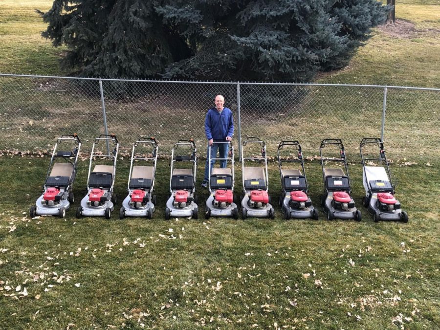 Michael Luque, the man with many mowers, standing in front of nine of the lawn mowers in his collection.