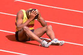 Man sits in distress on track after a sports injury occurs